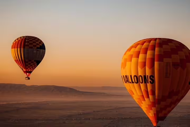 Two colorful hot air balloons flying at sunrise over Luxor desert, Egypt, morning ride with transfer