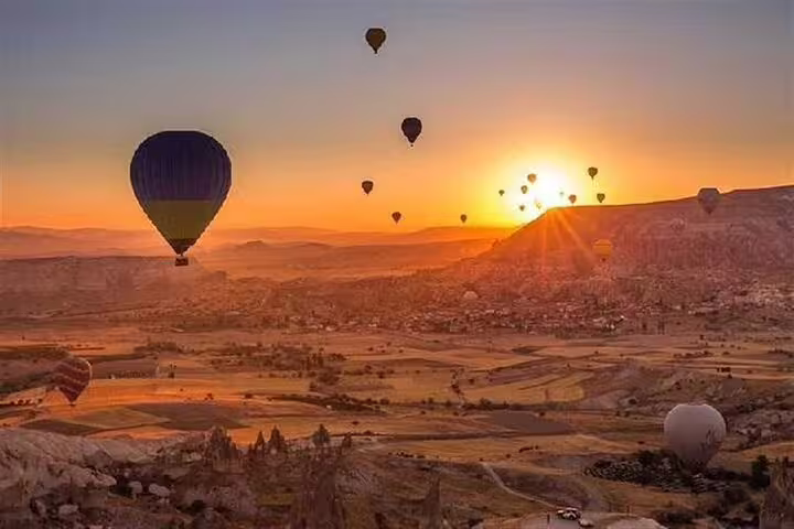 Hot air balloons at sunrise over Luxor landscape on a scenic balloon flight, with pickup and drop-off