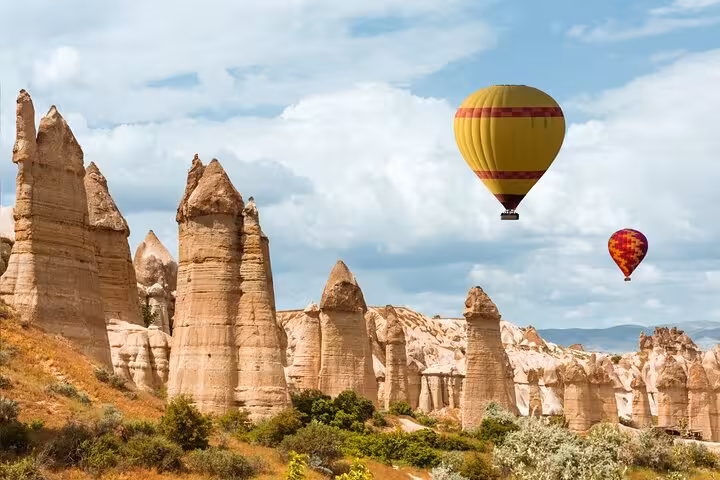 Hot air balloons over Cappadocia fairy chimneys on daily tour from Istanbul hotels, iconic Göreme landscape