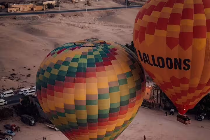 Colorful hot air balloons inflating in Luxor before sunrise flight, with pickup and transfer to launch site