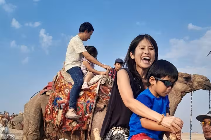 Family enjoying camel ride near Giza Pyramids on Hurghada to Cairo private tour with Grand Egyptian Museum stop