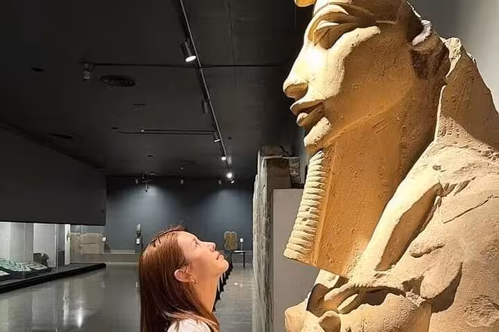 Traveler viewing ancient Egyptian statue in Grand Egyptian Museum, guided Hurghada to Cairo day trip