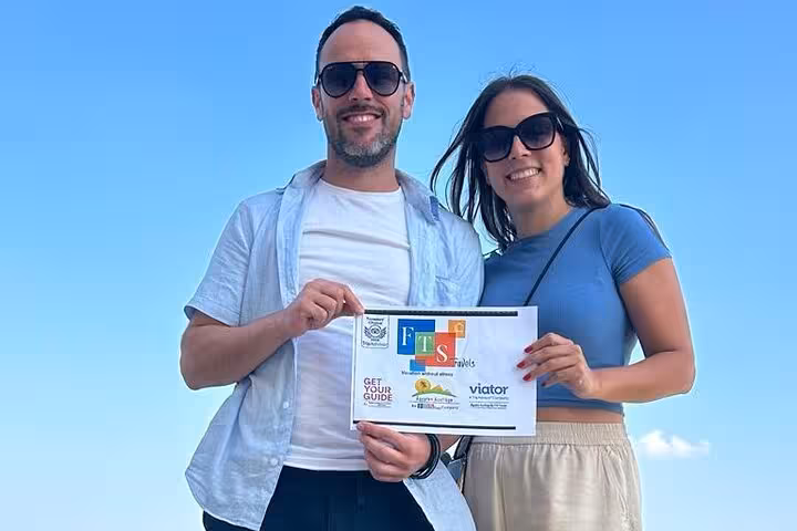 Happy couple holding tour sign before Hurghada to Cairo trip with Giza Pyramids and Egyptian Museum guided visit