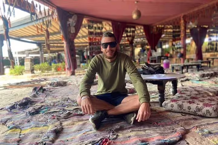 Traveler relaxing in a Bedouin camp lounge after quad bike desert safari, ready for camel ride and dinner experience
