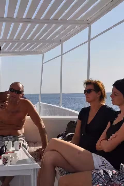 Guests relaxing on a Hurghada boat deck during a Red Sea dolphin swim tour with snorkeling and sunbathing