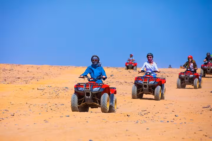 Family riding ATV quad bikes across Hurghada desert on safari tour with Jeep dinner and show experience