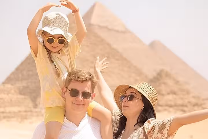 Family posing by the Giza Pyramids on a Hurghada small-group Cairo day trip with Grand Egyptian Museum visit