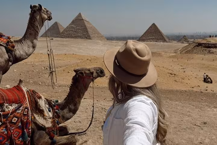 Traveler with camels overlooking the Giza Pyramids, part of a Hurghada small-group Cairo day tour and GEM visit