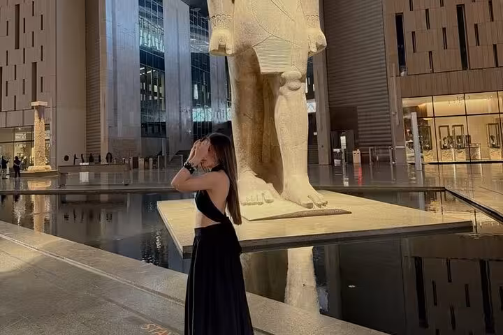 Traveler at Grand Egyptian Museum entrance beside colossal statue on Hurghada to Pyramids small-group tour