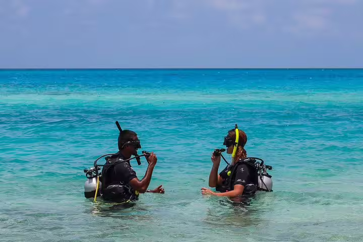 Hurghada intro scuba lesson in shallow Red Sea water, two divers practicing breathing with instructors