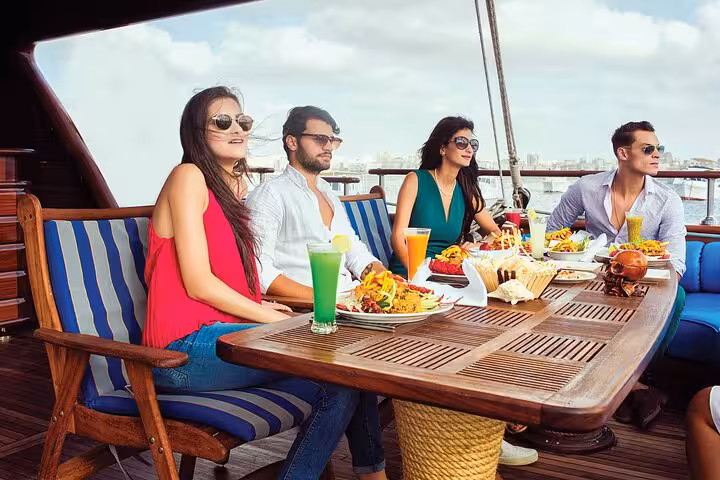 Friends enjoy onboard buffet lunch and drinks on Hurghada pirate sailing boat trip to Orange Bay island