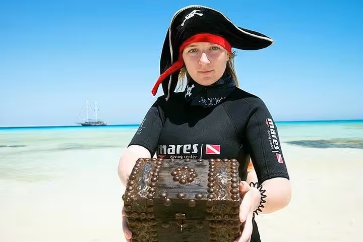 Pirate crew member holding treasure chest at Orange Bay on Hurghada Pirates sailing boat tour with snorkeling and lunch