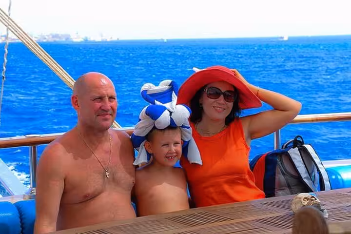 Family relaxing on deck during Hurghada pirates sailing boat to Orange Bay tour, enjoying Red Sea cruise and buffet