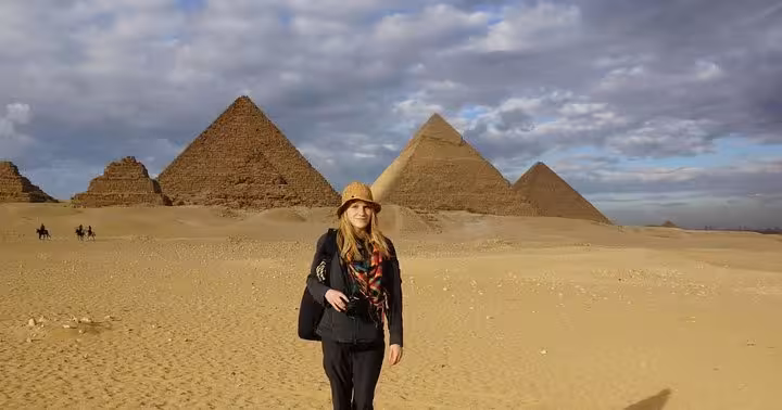 Traveler in Sahara desert with Giza Pyramids backdrop, Cairo day tour experience from Hurghada 3 days