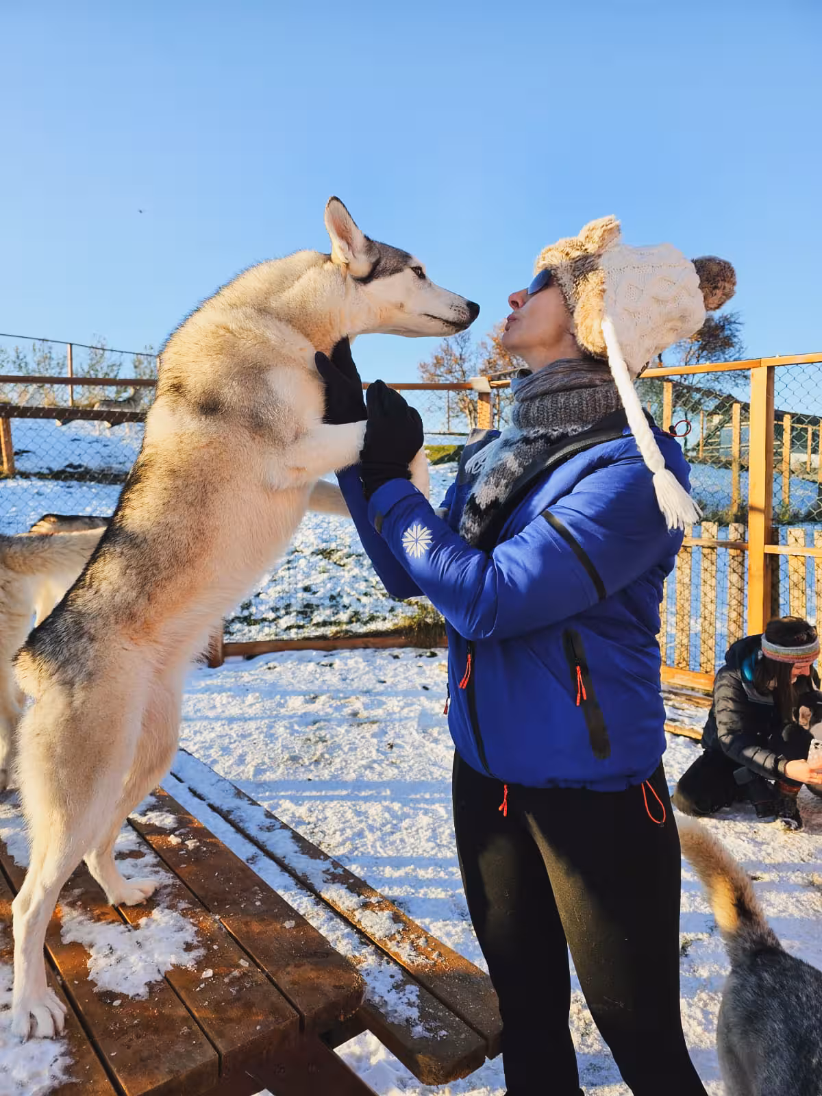Traveler bonding with husky at winter dog sled camp, private Arctic Odyssey huskies and aurora tour