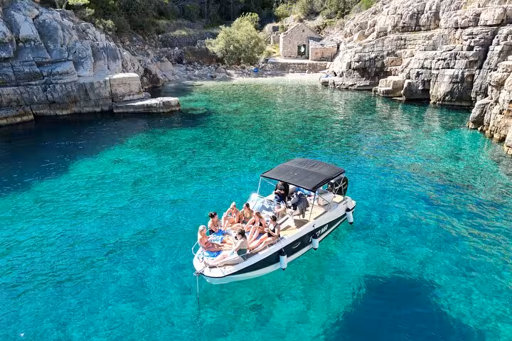 Private boat tour in Hvar Island north shore cove, swimmers relaxing on a speedboat in turquoise Adriatic water