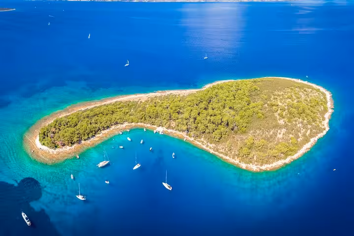 Drone view of Zecevo Islet near Hvar, turquoise lagoon and anchored yachts on a private boat tour
