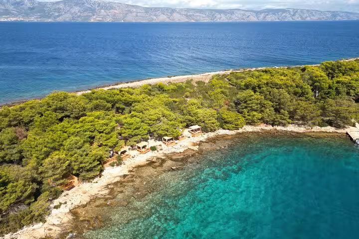 Aerial view of Hvar north shore cove with turquoise water and pine forest on private boat tour
