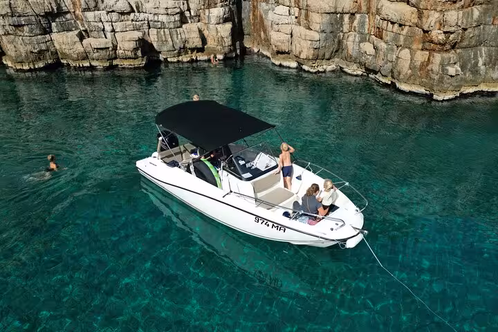 Private boat tour near Hvar North Shore cliffs, anchored in crystal-clear water for swimming stop