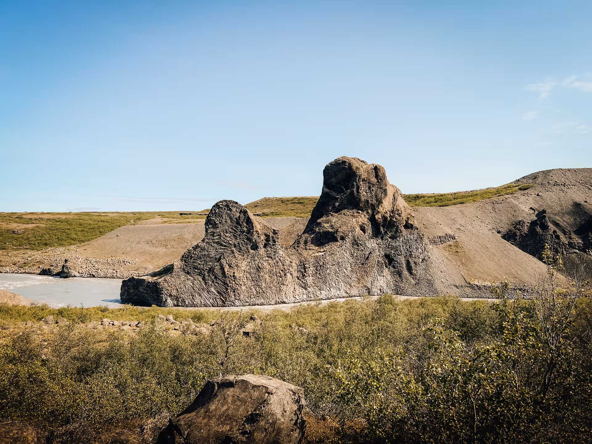 Rugged volcanic rock formations by a river valley, dramatic geology on Iceland Adventure Diamond Circle Tour