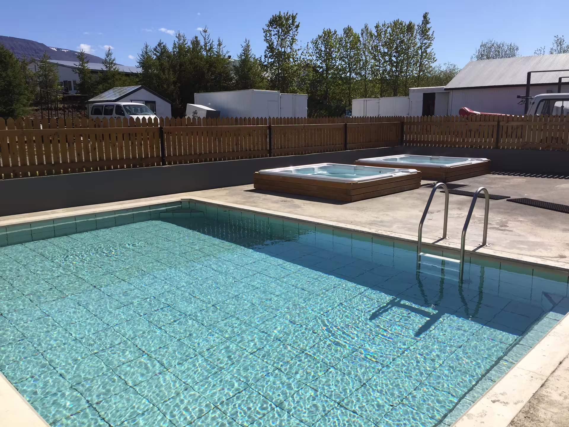 Outdoor pool and hot tubs at a scenic Icelandic retreat, perfect for relaxing after a West Glacial River rafting adventure.