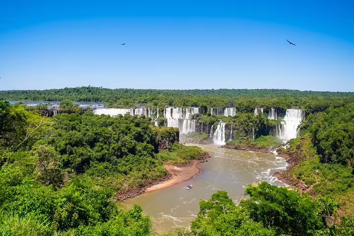 Aerial view of Iguazu Falls with a boat navigating the river, showcasing the beauty of this must-see Brazilian attraction.