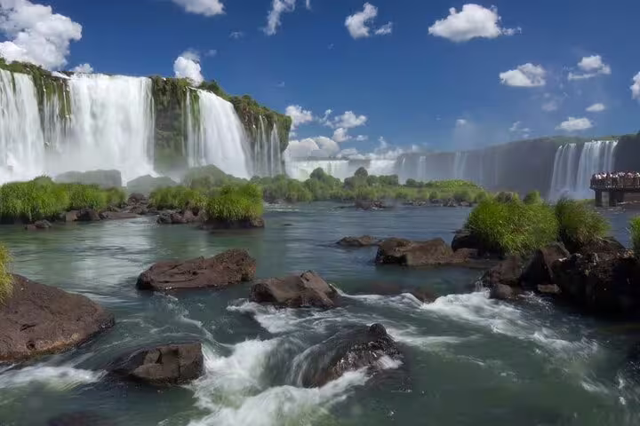 Scenic panorama of Iguazu Falls with lush greenery and flowing water, perfect for a shared guided tour experience.