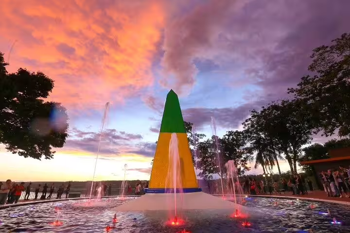 Vibrant sunset over the Iguazu Falls with colorful monument and fountains, perfect for 4-day shared guided tour.