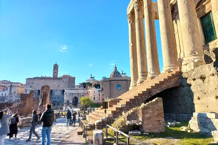 Scenic view of the Imperial and Palatine Forums with ancient ruins and columns under a clear blue sky.