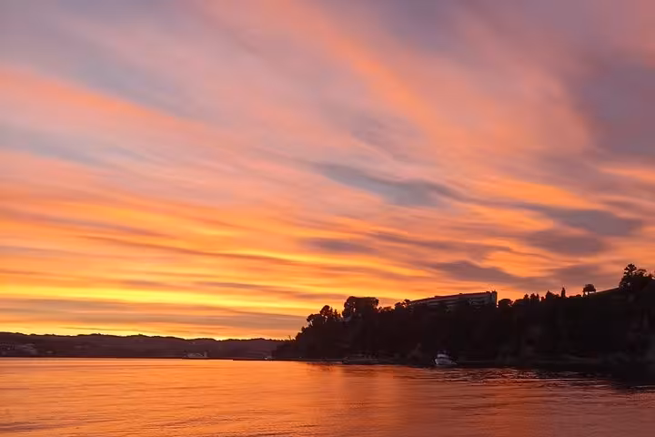 Golden Ionian Sea sunset over tranquil coastline on a local BBQ boat tour, pastel sky and calm bay