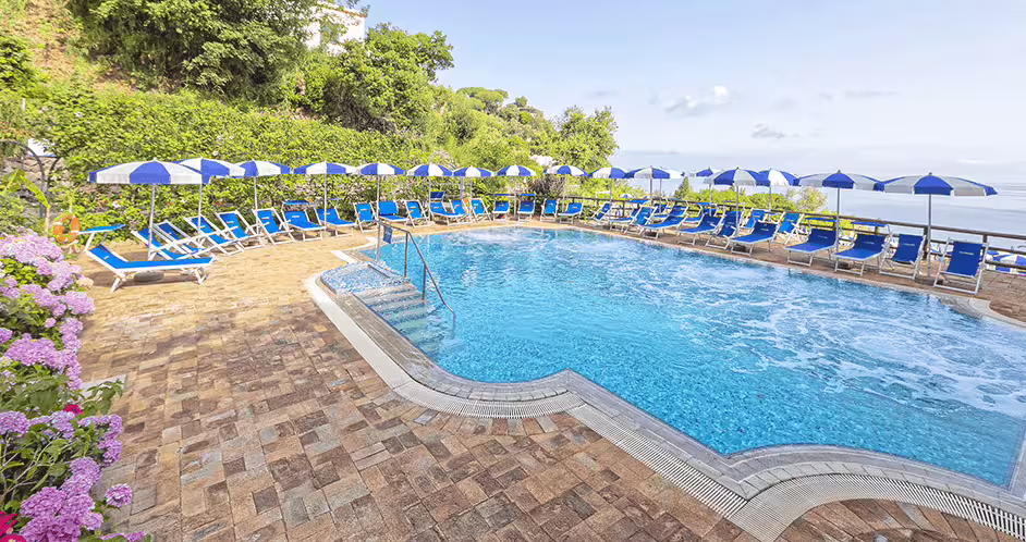 Piscina panoramica con acqua termale e idromassaggio al Parco Castiglione Ischia, circondata da ombrelloni e fiori