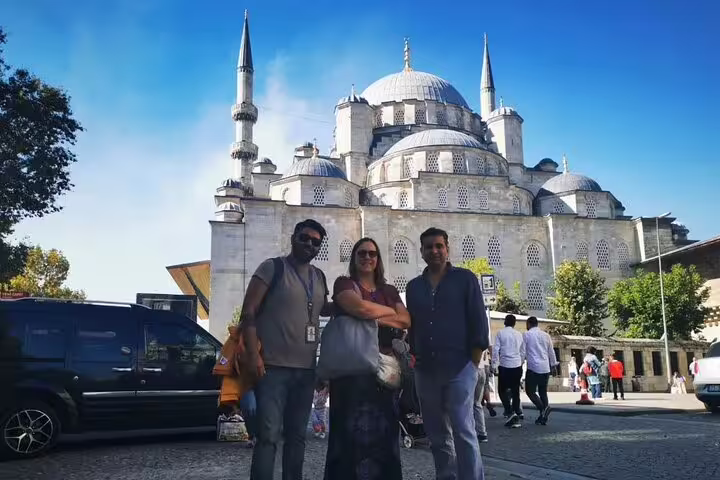 Three visitors standing in front of the iconic Blue Mosque on a sunny day during a private Istanbul tour.
