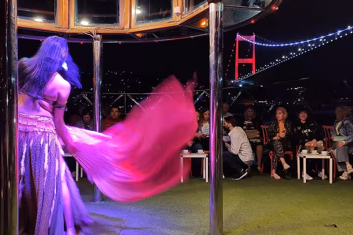 Belly dancer performing Turkish night show on Istanbul Bosphorus dinner cruise with guests dining onboard