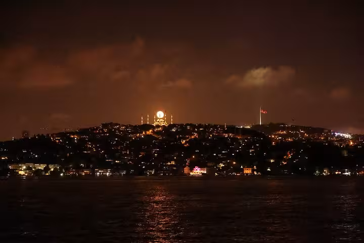 Night view of Istanbul skyline from Bosphorus dinner cruise with illuminated mosque and city lights