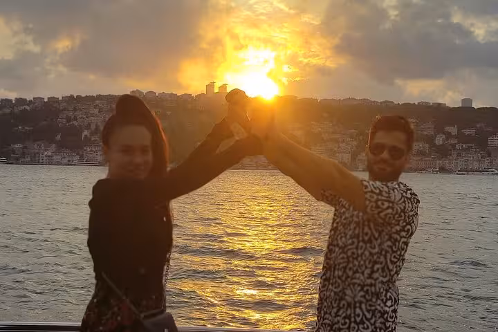 Friends toast at golden sunset on a Bosphorus luxury yacht cruise in Istanbul, with waterfront views behind