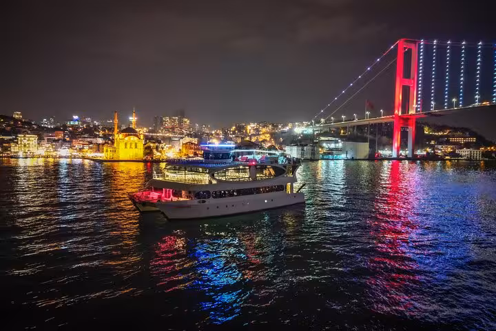 Istanbul Bosphorus New Year’s Eve dinner cruise yacht passing Ortakoy Mosque and illuminated Bosphorus Bridge