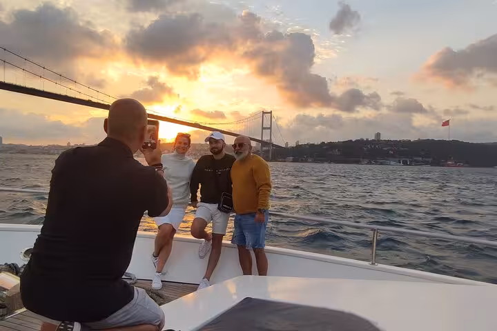 Friends posing for photo on luxury Bosphorus sunset cruise yacht in Istanbul with bridge backdrop