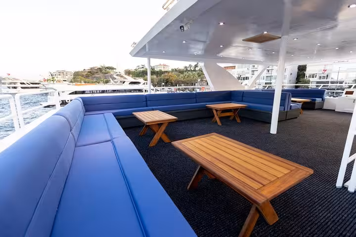 Spacious upper deck seating on private Istanbul Bosphorus yacht cruise with lounge sofas and teak tables