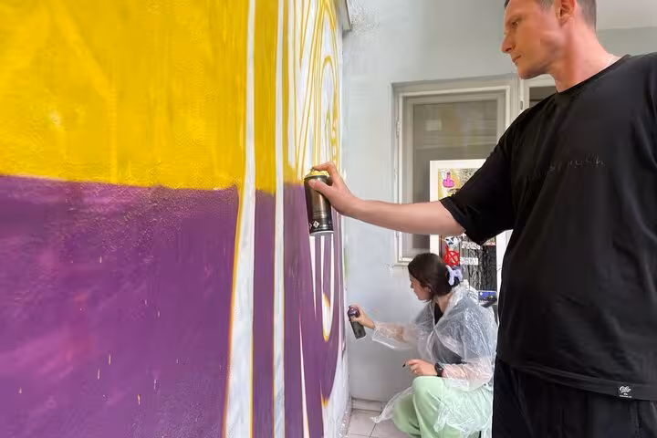 Street art workshop in Istanbul neighborhood, travelers spray-paint mural during 3-day local life immersion trip