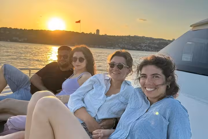 Friends relaxing on a luxury yacht during an Istanbul Bosphorus sunset cruise with golden hour skyline