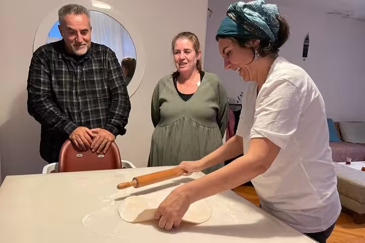 Local host rolling dough in an Istanbul home vegan vegetarian cooking class with guests watching nearby
