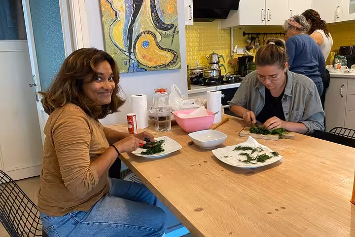 Guests chop fresh herbs in a local Istanbul home kitchen during a vegan vegetarian cooking class