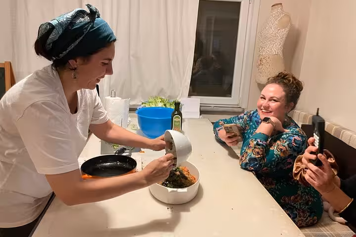 Local host prepares vegan Turkish dish in an Istanbul home cooking class while guests watch and film the process