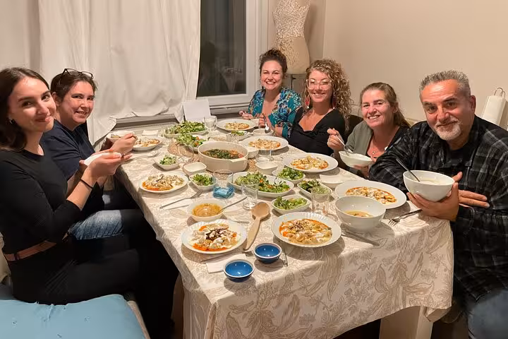 Guests enjoy homemade vegan Turkish meze at a local Istanbul home cooking class, sharing a festive table