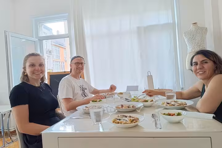 Travelers taste vegetarian Turkish mezze at a bright Istanbul home cooking class with locals, seated at the table