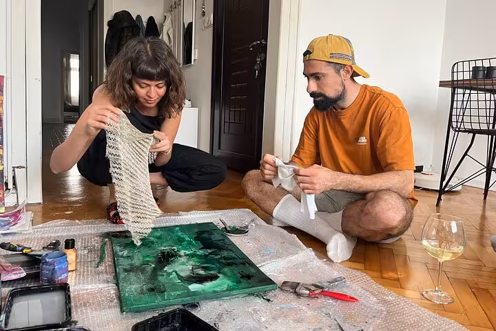 Couple enjoys Istanbul wine and paint experience at a local’s home, creating abstract art on the floor