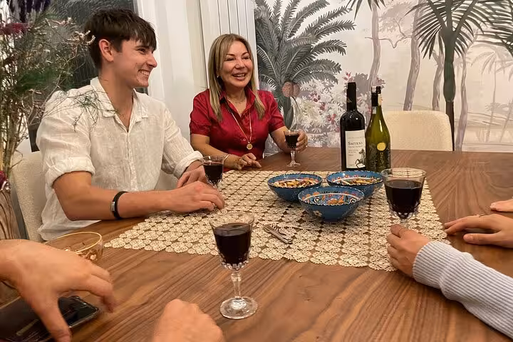 Guests tasting Turkish red wine with a local Istanbul family at home, sharing snacks around the table