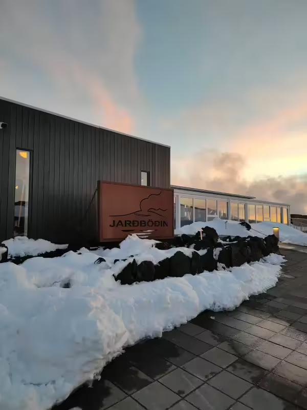 Jardbodin Nature Baths entrance sign covered in snow at sunset near Myvatn Lake, Iceland