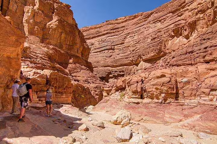 Hikers exploring Canyon Salama sandstone walls on Jeep safari day trip from Sharm El Sheikh to Dahab
