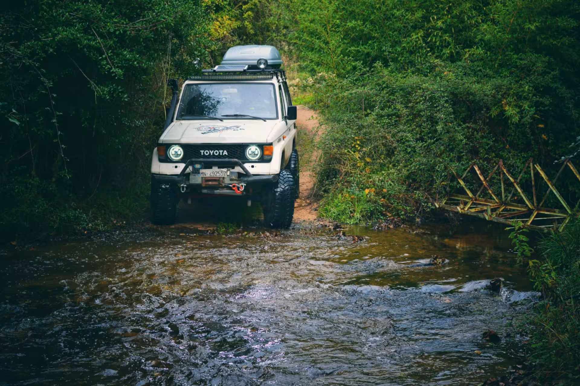 Off-road jeep crossing a stream surrounded by dense greenery on an adventurous Mount Limbara tour.